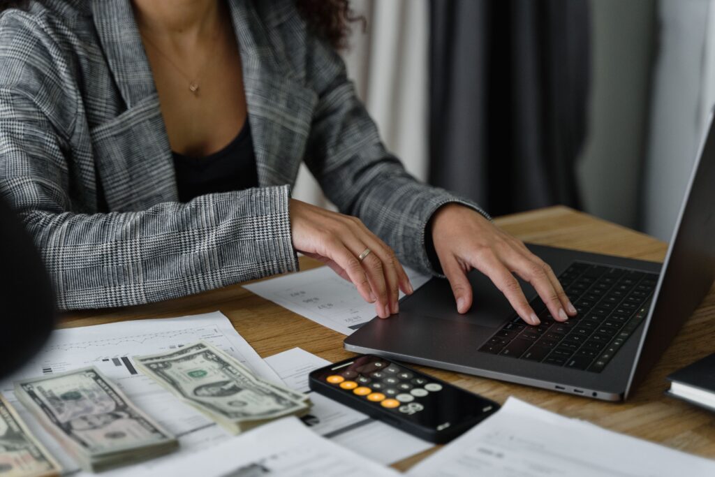 Business owner comparing the annual cost of an in-house accountant versus outsourced accounting on a calculator with financial statements