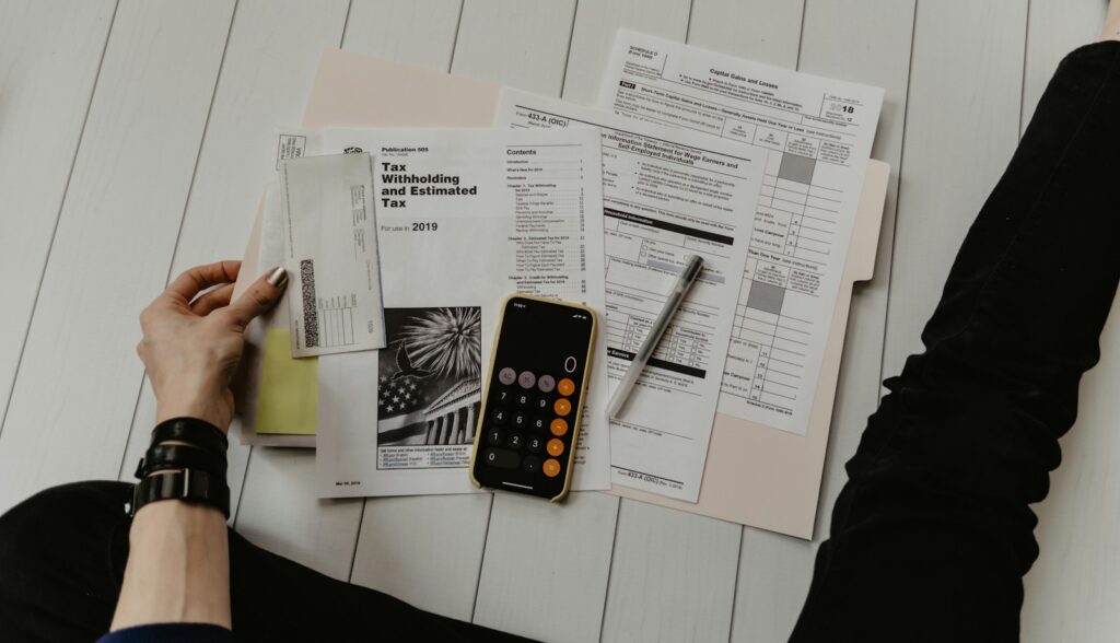 Tax forms, schedules and a calculator on a desk during a year-end accounting close